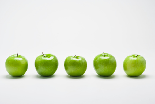 A row of five organic green Granny Smith  apples with position appropriate reflections and shadows  on white background