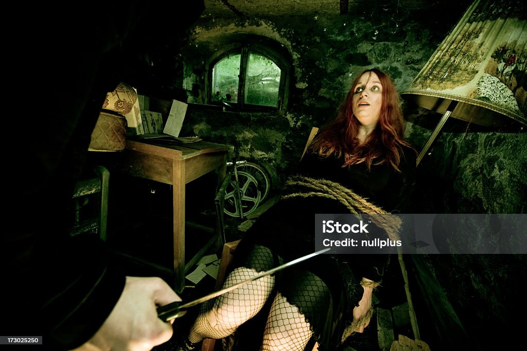 Young Woman Tied to Chair with Man's Hand Holding Knife young woman tied to a chair in a dirty cellar Women Stock Photo