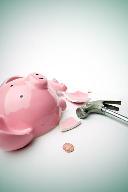 istock A smashed pink piggy bank with a hammer next to it  173025869