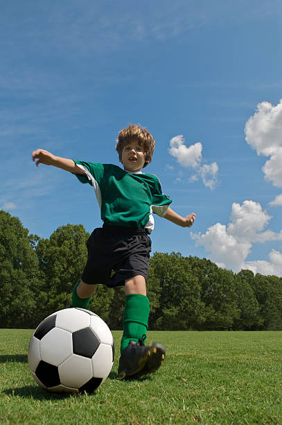 istock boy in green kicking soccer ball 173026056
