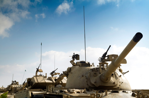 A line of tanks headed to battle, with a blue sky overhead available for copy space.