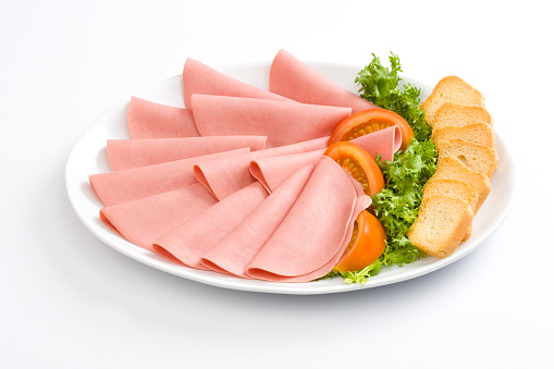 Ham (Bologna) or sausage with tomato, lettuce and toast bread in a white dish in a white background