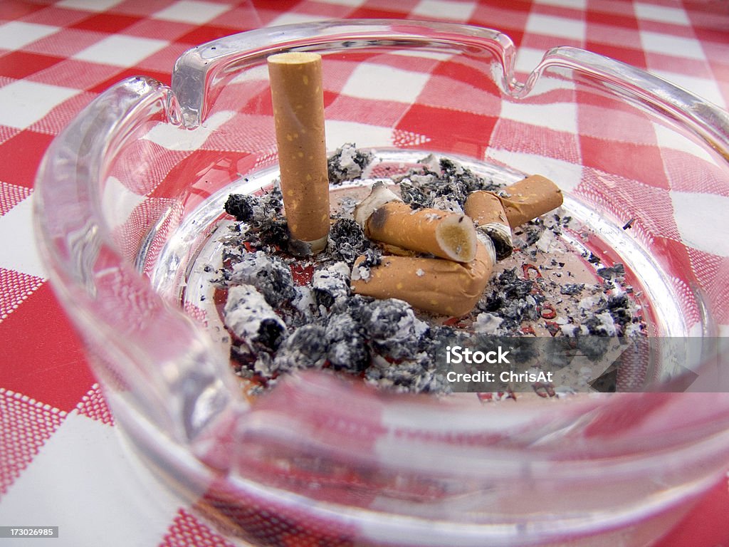 Smoking Cigarette butts stubbed out in glass ashtray Ashtray Stock Photo