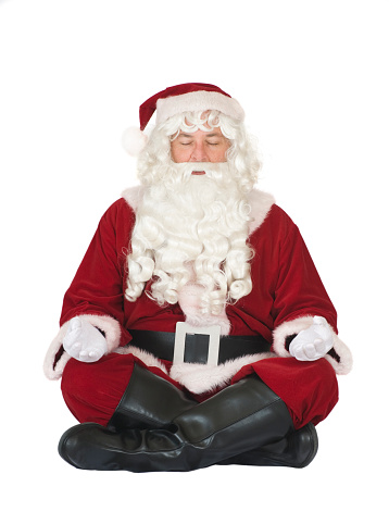 Santa relaxed sitting in a yoga position on the floor, meditating in preparation for the hectic season ahead.   Isolated on white.