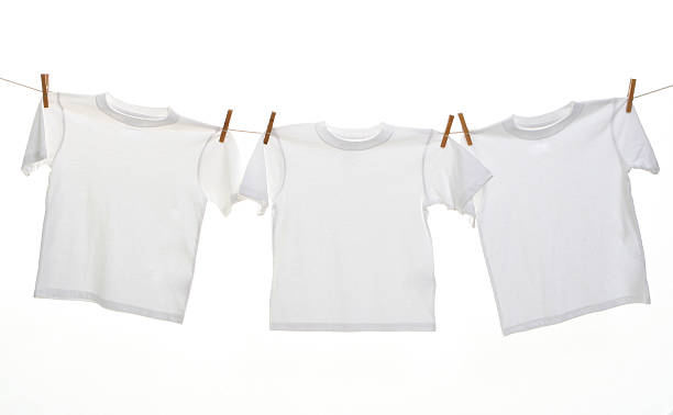 Three white t-shirts hanging on a line with clothes pins stock photo