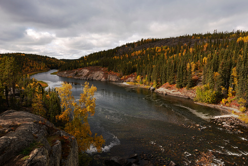 Autumn along the Cameron River in Canada's Northwest Territories.  Overcast clouds with a bit of sun on the land