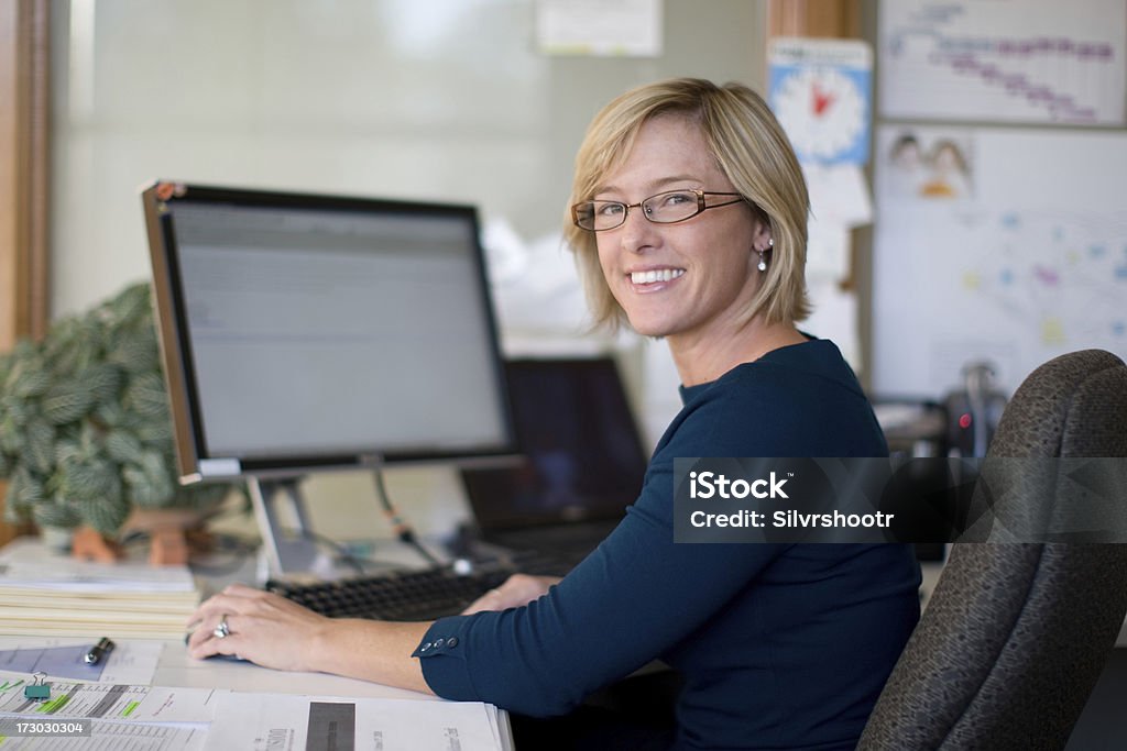 Mid thirties female professional A woman in her mid thirties sits at a desk in front of a computer screen.Please see some similar pictures from my portfolio: Secretary Stock Photo