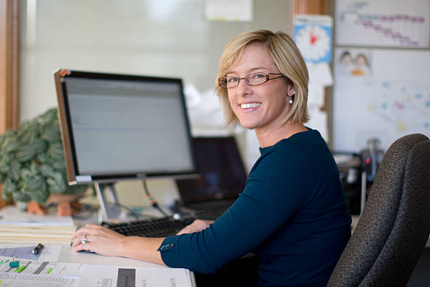 Mid thirties female professional A woman in her mid thirties sits at a desk in front of a computer screen.Please see some similar pictures from my portfolio: in front of stock pictures, royalty-free photos & images