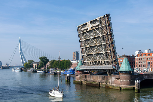 Rotterdam, the Netherlands-September 10, 2023; Open bridge decks of the Koninginnebrug with sailboat passing by in the Koningshaven with Noordereiland and Erasmus bridge in background