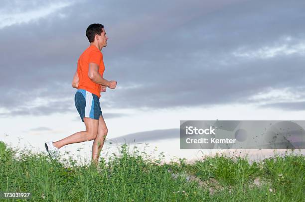 Running Maschio Adulto Con Un Top Arancione E Pantaloncini Blu - Fotografie stock e altre immagini di Abbigliamento sportivo
