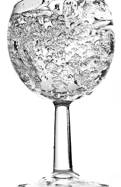 Water bubbling in a wine glass against a white background
