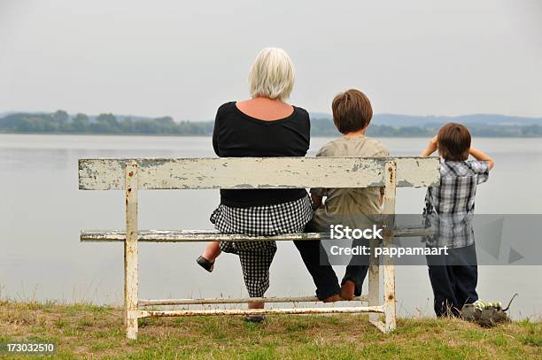 Photo libre de droit de Mamie Avec Grandsons Sur Un Banc Au Bord De Leau banque d'images et plus d'images libres de droit de Regarder - Regarder, Enfant, Troisième âge