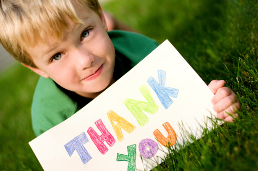 Little boy holding a thank you sign.  