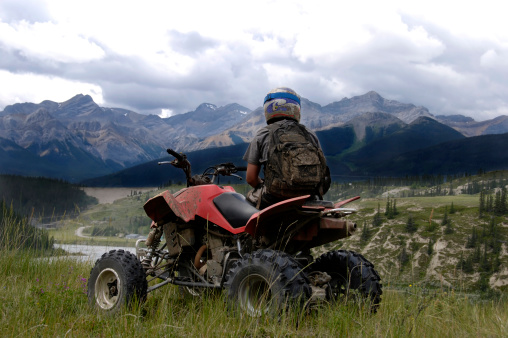 A man looking at the mountains on his quad.