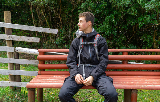 A young individual sits on a bench, patiently waiting to commence their trekking adventure.
