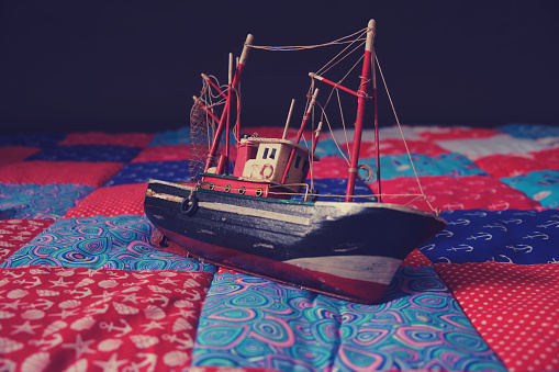 Vintage toy boat on the quilt. Retro style toned picture