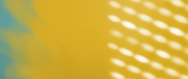 Shadow from the blinds on the concrete wall on a sunny day, Interior design. Abstract background, banner, pattern, texture. Blue, white, yellow colors.  Copy space.