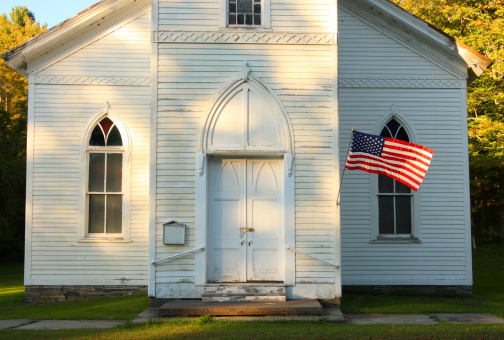 Flag waving in front of old church on summer afternoon.