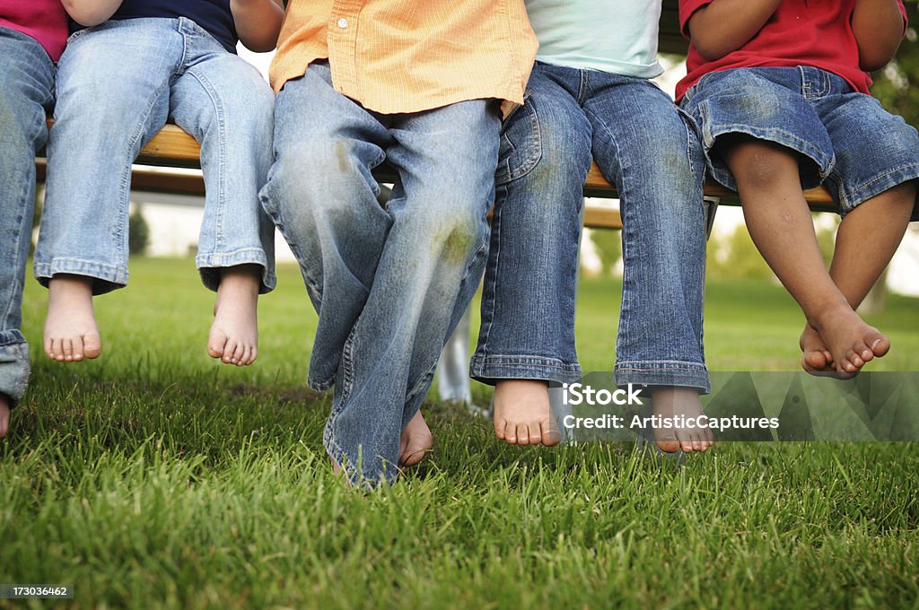 Dirty Legs and Feet of Children Sitting on a Bench Color photo of the bare feet of little kids sitting on a picnic table. Stained Stock Photo