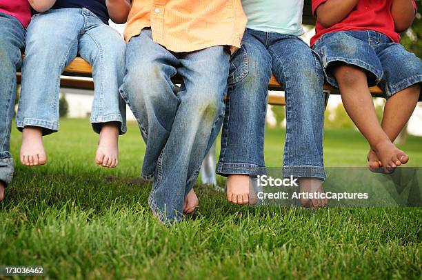 Dirty Legs And Feet Of Children Sitting On A Bench Stock Photo - Download Image Now - Stained, Grass, Child