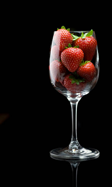 Strawberries in wine glass on black background stock photo