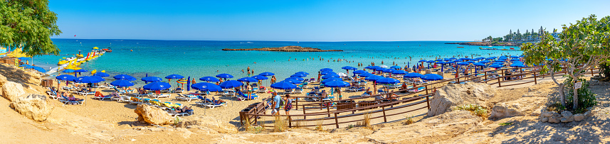 Sand beach with crystal clear waters of Fig Tree Bay with a small island on the horizon and numerous water activities, September 2023 in Cyprus