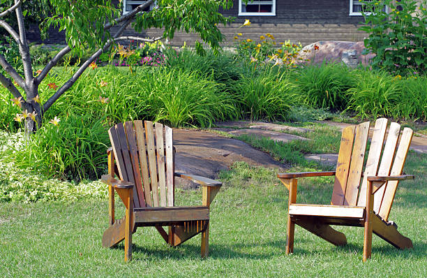 Muskoka Chairs Pair of Adirondack Chairs (known as Muskoka Chair in Canada) before flower beds, green lawn of a cottage huntsville ontario stock pictures, royalty-free photos & images