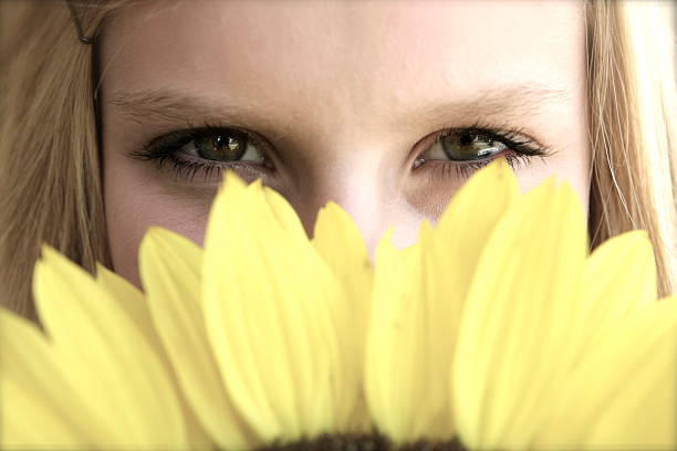 front view of little girl with blue eyes with orange flower in head staring at camera.