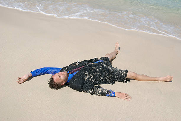 naufrago uomo d'affari si trova sulla sabbia morbida lavata a terra - stranded beached beach businessman foto e immagini stock