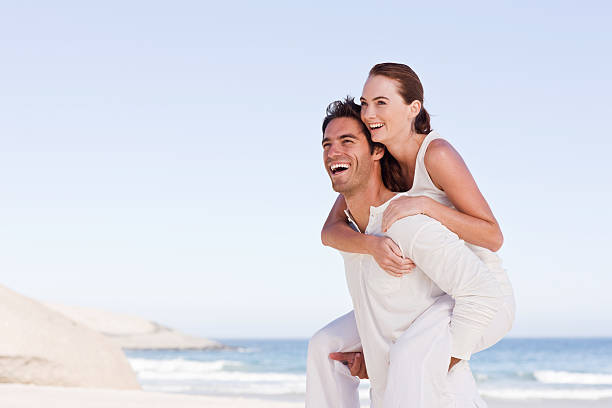 istock Happy young man holding woman on back at beach 173042159