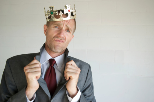 Royal bing businessman popping his collar and throwing a cocky expression to the camera with a tilted crown on his head
