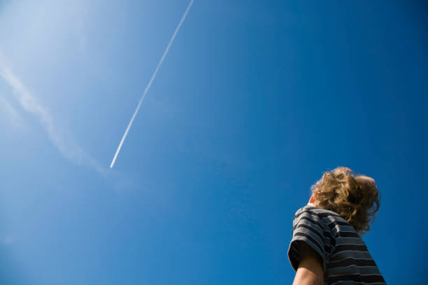 Boy looking at Jet Smoke Boy looking at jet smoke looking up stock pictures, royalty-free photos & images