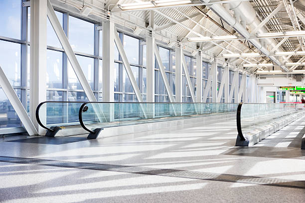 aeropuerto de un pasillo mecánico con ventanales, luz natural, vacío - cinta mecánica fotografías e imágenes de stock