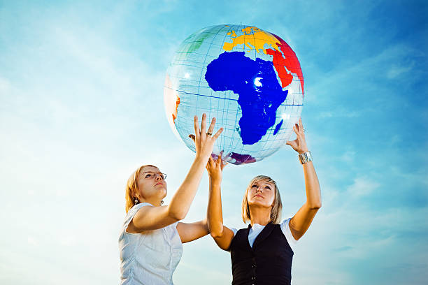 istock Two young ladies holding up inflatable globe 173043231