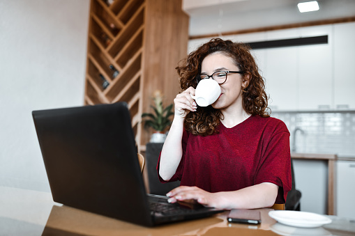 Smiling Female Drinking Coffee During Video Conference On Laptop