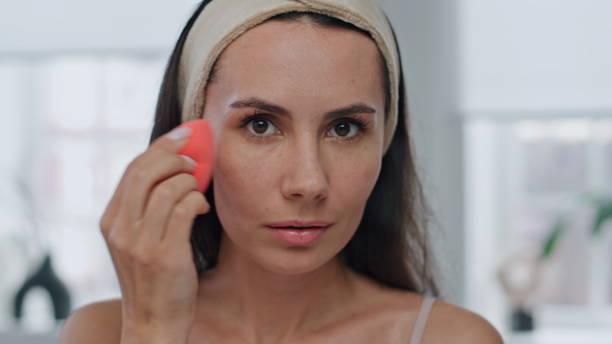 istock Makeup woman using sponge tool home mirror pov portrait. Lady preparing makeup 1730465724