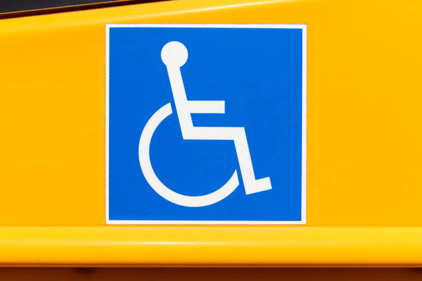 Handicapped wheelchair access logo sign on a yellow school bus.