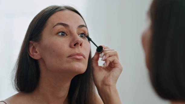 istock Confident woman applying mascara mirror place. Beautiful model preparing makeup 1730479758