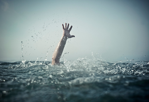 Hand reaching out of deep water, focus on water splash