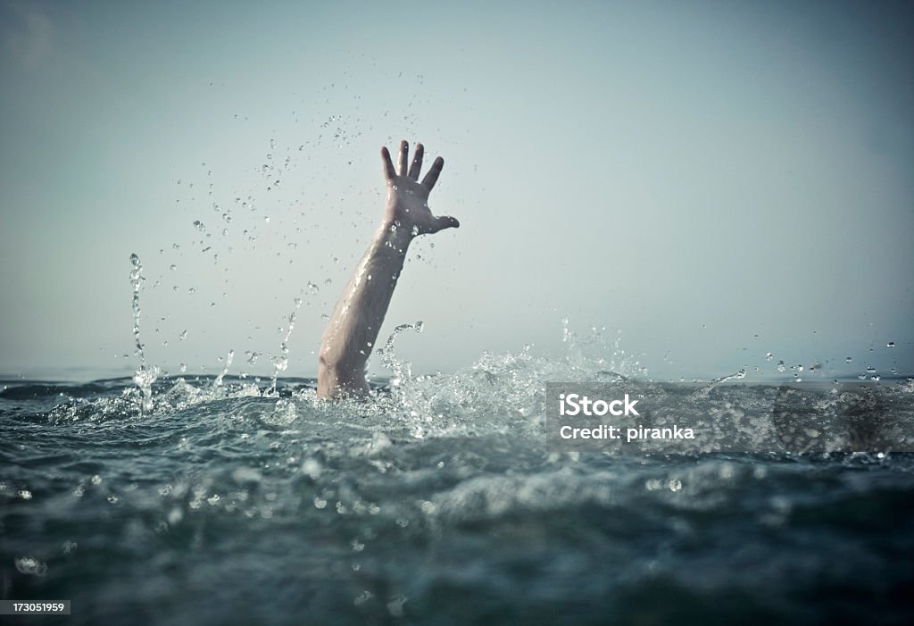 Hand emerges splashing water from below Hand reaching out of deep water, focus on water splash Drowning Stock Photo
