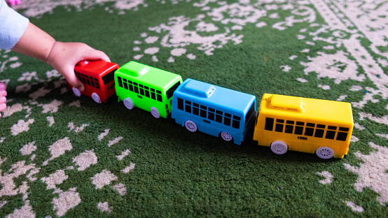 A child playing with colorful toy bus at home
