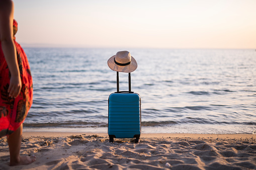 a suitcase with luggage and a summer hat on the beach.