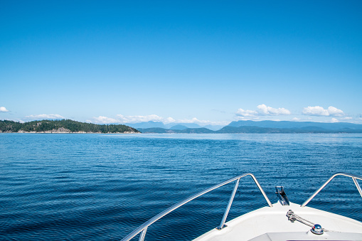 Looking off the bow of a white speedboat towards mainland Canada and the Strait of Georgia.