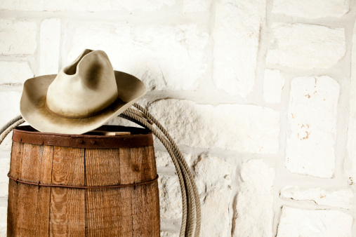 Cowboy hat and lasso on barrel. Austin sandstone background