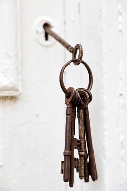 A set of antique keys in the lock of an old English door.