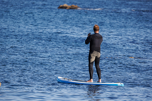 A Man paddle boarding in the pacific ocean near Monterey, California