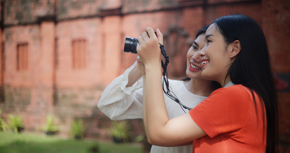 Portrait of A joyful Asian women exploring an ancient temple, capturing cherished moments on their vacation through photographs. Travel, people and lifestyle concepts.