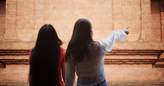 Portrait of A joyful Asian women exploring an ancient temple, capturing cherished moments on their vacation through photographs. Travel, people and lifestyle concepts.