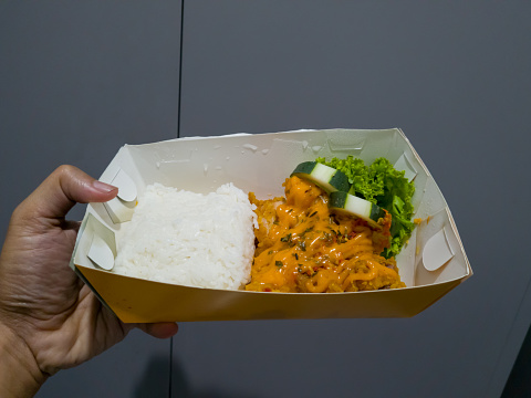 Chicken rice sprinkled with cheese mayonnaise in a white paper container