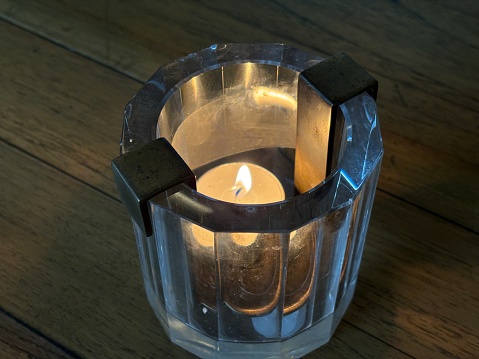 Small candle lit in a glass